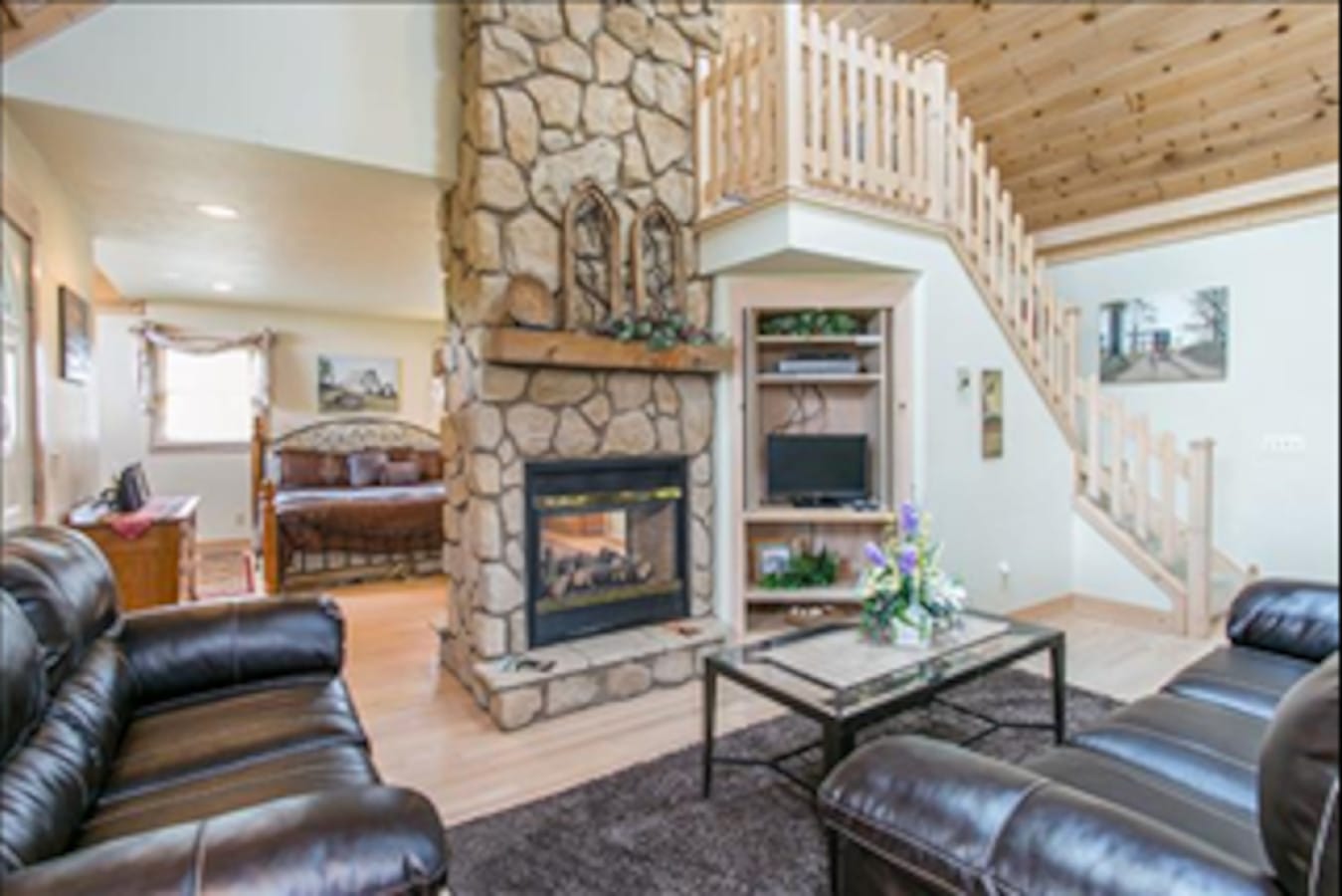 Two-story stone fireplace and loft inside Premier Cottage #3 at Premier Cottages, Berlin Ohio