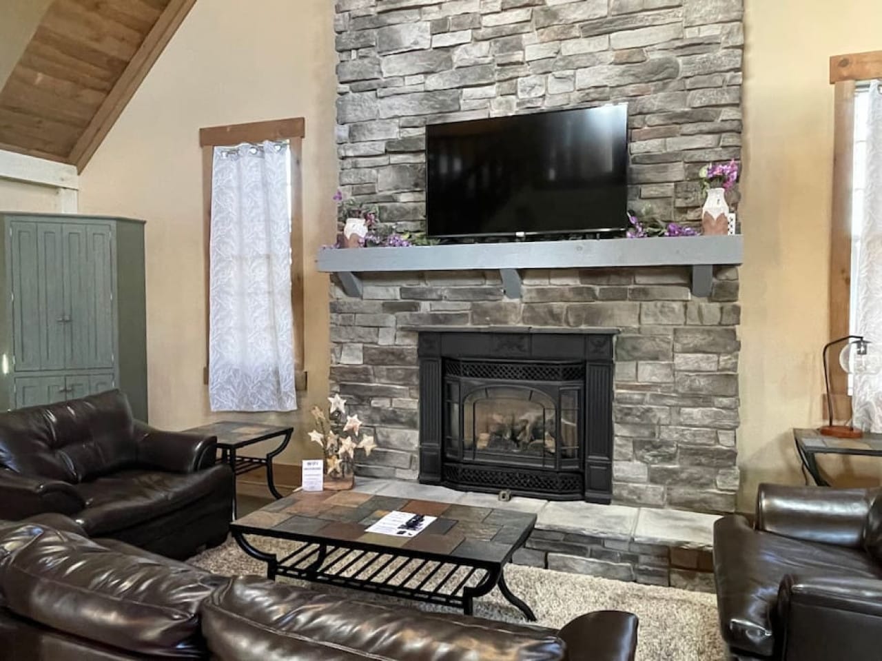 Living room with stone fireplace inside Premier Cottage #6 at Premier Cottages, Berlin Ohio